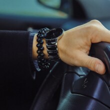 Color image of adult male hand with watch and bracelet in car. Close up photo.